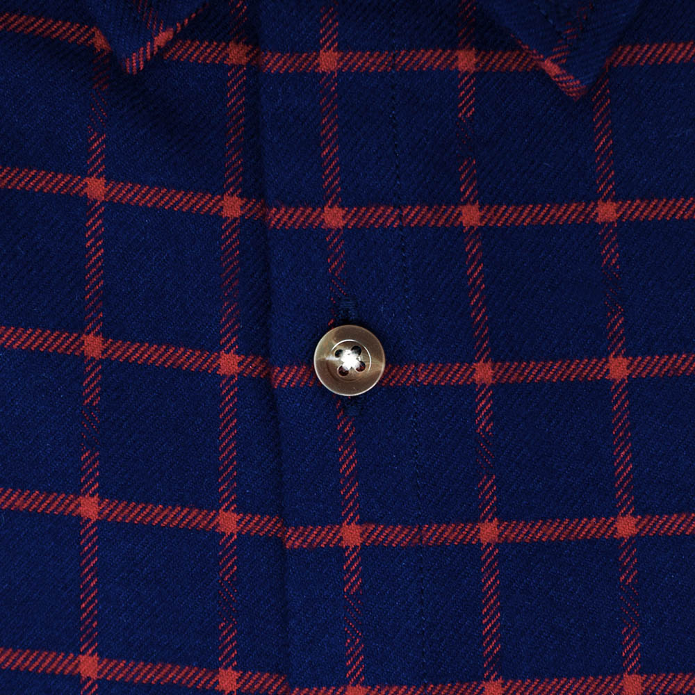close up of button and fabric detail on a red and blue plaid shirt