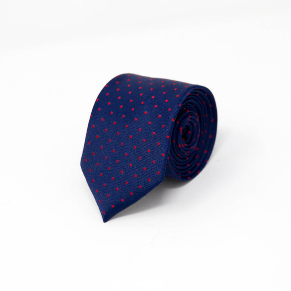 Navy blue tie with red polka dots, rolled up, on a white background.