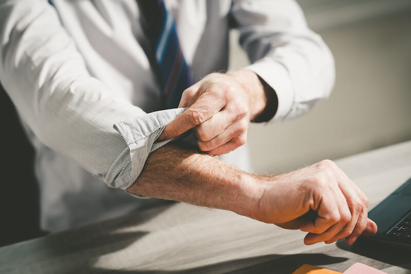 man wearing dress shirt rolling up his sleeves at work