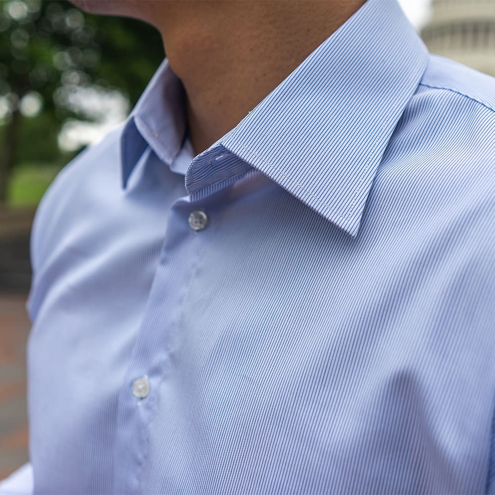 pointed collar of a light blue striped dress shirt